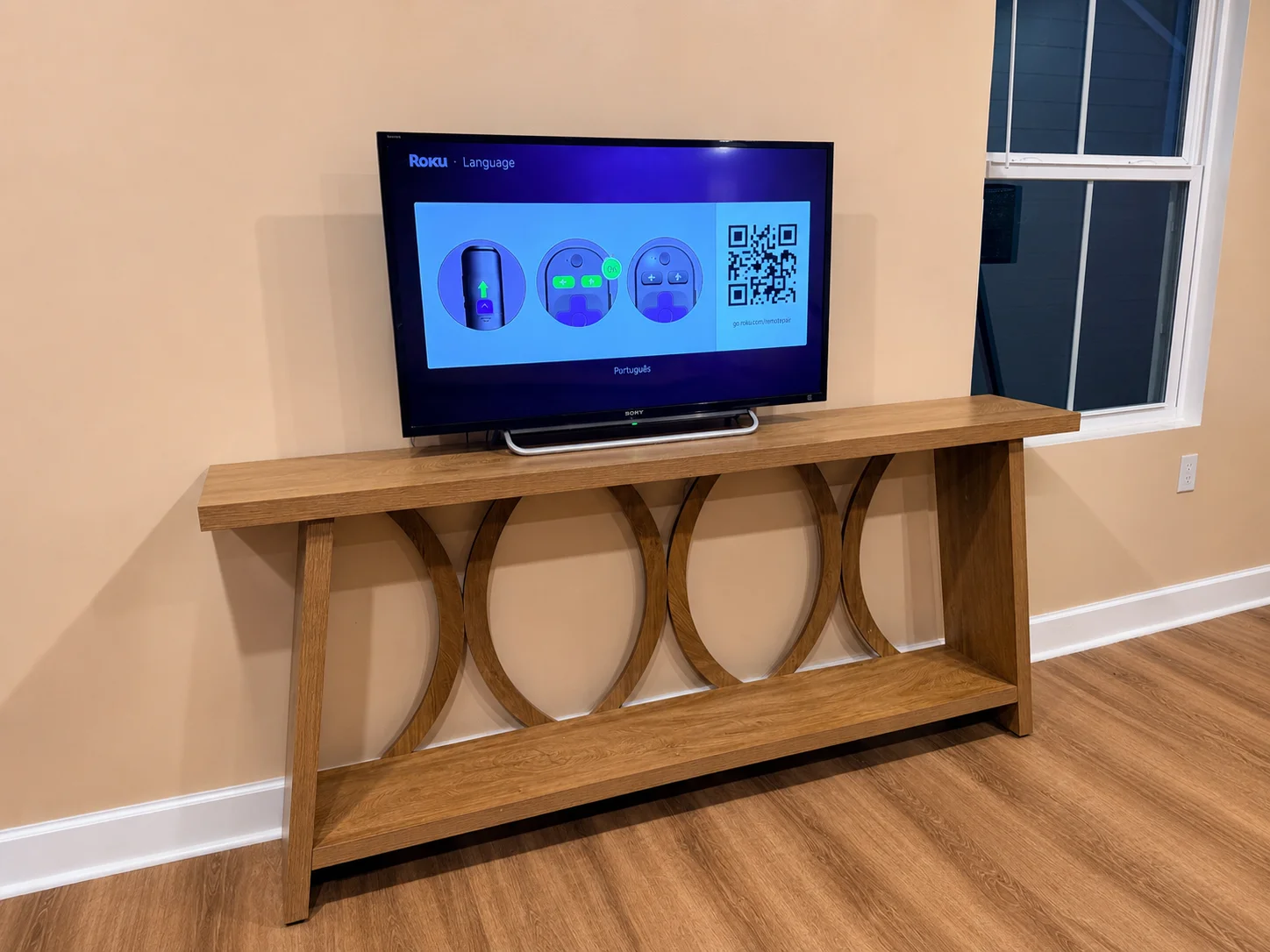Boxed2Built A newly assembled wood console table with open decorative supports positioned against a wall in a home.