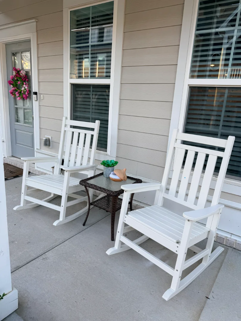 Two white oversized HDPE rocking chairs fully assembled on a front porch beside a small table and decorative lanterns at a home in Spring Hill, Tennessee. The outdoor furniture was assembled by Boxed2Built as part of a patio furniture setup service.